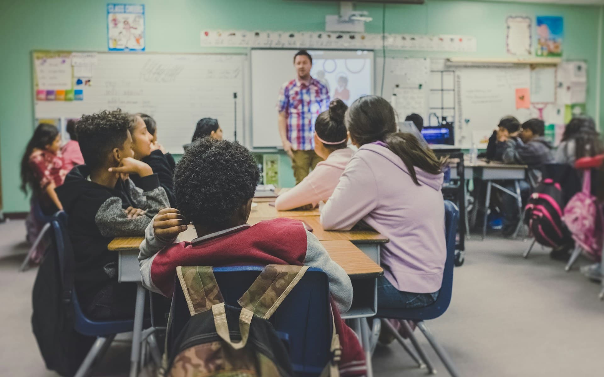 Une enseignante présente des consignes à des élèves réunis en classe